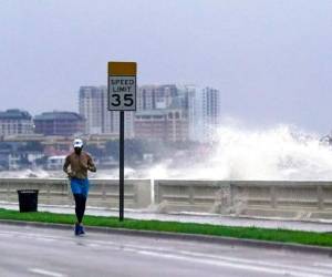 Un corredor pasa por el Bulevar Bayshore en Tampa, Florida, mientras una ola rompe sobre el muelle tras el paso de la tormenta tropical Elsa, el miércoles 7 de julio de 2021. Foto: AP