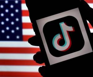En esta ilustración fotográfica, el logotipo de la aplicación de redes sociales, TikTok, se muestra en la pantalla de un iPhone sobre un fondo de bandera estadounidense. Foto: AFP