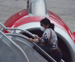 Una mujer que aborda una línea aérea usa una máscara protectora como precaución contra la propagación del nuevo Coronavirus, COVID-19, en el Aeropuerto Internacional Toncontin, en Tegucigalpa. AFP.