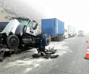 Dos personas trabajan para despejar la carretera tras una colisión múltiple en la interestatal 15 en Cajon Pass, cerca de Hesperia, California, el miércoles 16 de enero de 2019.