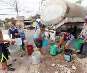 Un grupo de vecinos de la colonia San Miguel llena sus baldes al momento en que llegó una cisterna del SANAA.