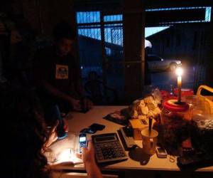 Con linternas y teléfonos celulares se alumbran los pobladores del valle de Sula ante los constantes apagones.