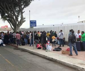 Los solicitantes de asilo en Tijuana, México, escuchan los nombres que se llaman desde una lista de espera para solicitar asilo en un cruce fronterizo en San Diego, el jueves 26 de septiembre de 2019.