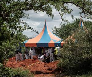 Los trabajadores se refugian mientras cavan el suelo para exhumar los cuerpos de la fosa común en Shakahola.