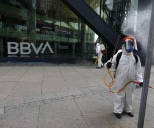Trabajadores municipales rocían desinfectante frente al edificio del banco BBVA sobre la avenida Paseo de la Reforma por la pandemia de coronavirus, en la Ciudad de México, el lunes 6 de abril de 2020. Foto: Agencia AP.