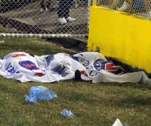 Los cuerpos de las víctimas se ven cubiertos con banderas de Alianza luego de una estampida durante un partido de fútbol entre Alianza y FAS en el estadio Cuscatlán en San Salvador, El Salvador.