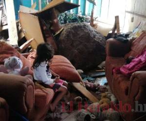 Una de las nietas de don Rigoberto observa sus juguetes y la televisión aplastadas bajo la roca. Foto: Estalin Irías/El Heraldo.