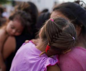 En esta foto del 30 de agosto de 2019, dos mujeres y sus hijas, entre decenas de migrantes, muchos de los cuales fueron devueltos a México bajo el programa 'Permanecer en México' del gobierno de Donald Trump, hacen fila para comer en un campamento cerca del Puente Internacional en Matamoros, México. Fotos: Agencia AP.