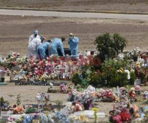 El cadáver fue cargado hasta su fosa por un grupo de cinco personas, integrado por personal de la Secretaría de Salud y Policías Militares. Foto: Emilio Flores/El Heraldo.