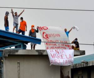 Reclusos sostienen carteles en lo alto de un techo en el penal Regional 8, contiguo al penal, en las afueras de Guayaquil, Ecuador, el 2 de octubre de 2021. Foto: Agencia AFP.
