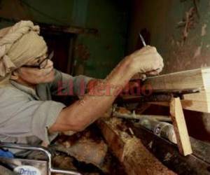 Con mucha precisión traza las líneas en la madera para luego tornearla.