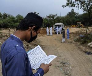 Un pariente lee los versos del Sagrado Corán cuando llega una ambulancia con el cadáver de una víctima que murió del coronavirus Covid-19 antes del entierro en un cementerio en Nueva Delhi. Foto: Agencia AFP.