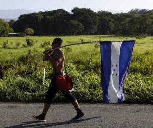 Un migrante hondureño lleva su bandera nacional mientras camina hacia el norte como parte de una caravana de miles de personas tratando de llegar a los Estados Unidos. Foto AP