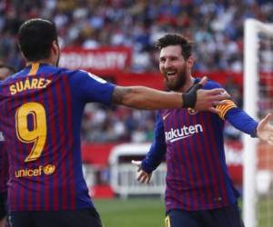 Lionel Messi festeja con su compañero Luis Suárez tras anotar su tercer gol en el partido de la Liga española, en Sevilla. (Foto: AFP)