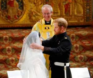 En esta foto del sábado 19 de mayo de 2018, el príncipe Enrique de Inglaterra levanta el velo de Meghan Markle ante el arzobispo de Canterbury Justin Welby durante la ceremonia de su boda en la Capilla de San Jorge, en el Castillo de Windsor, cerca de Londres. Foto: AP