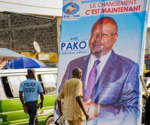 En esta imagen de archivo del domingo 7 de marzo de 2021, gente pasando junto a un cartel electoral del candidato opositor Guy Brice Pargait Kolelas en el centro de Brazzaville, República del Congo. Foto: AP
