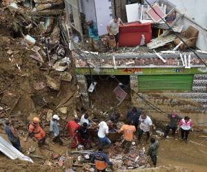 Las personas sacan el cadáver de una víctima de los escombros después de un deslizamiento de tierra en Petrópolis, Brasil, el 16 de febrero de 2022.