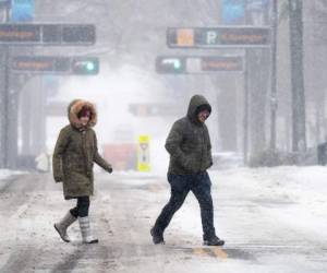Los peatones cruzan una calle en la nieve el 16 de enero de 2022 en Greenville, Carolina del Sur. La tormenta invernal trajo nieve, aguanieve y lluvia helada a partes de las Carolinas y Georgia, donde casi 300,000 personas quedaron sin electricidad. Foto: AFP