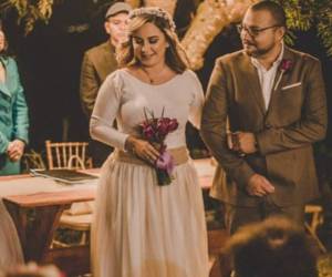 Muñoz optó por un vestido blanco y un ramo de tulipanes morados. Como accesorio usó una corona de flores que complementó con joyería discreta y un maquillaje natural.