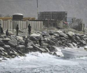 Fuerzas de seguridad vigilan el área costera y un bote en el que las autoridades dicen que un grupo de hombres armados desembarcaron en el puerto de La Guaira, Venezuela. Foto AP