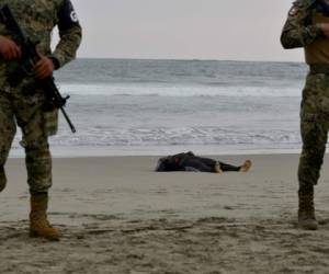 Fuerzas de seguridad forman un perímetro alrededor del cadaver de Emmanuel Cheo Ngu, de Camerún, en la orilla de la playa Boca Barra, en Puerto Arista, México, el viernes 11 de octubre de 2019. Fotos: Agencia AP.