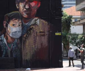 Un miral pintado recientemente muestra a un joven usando una máscara durante una cuarentena ordenada por el gobierno para evitar contagios por el nuevo coronavirus en Bogotá, Colombia, el lunes 13 de abril de 2020.