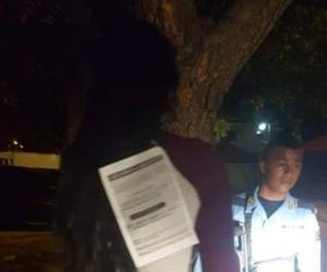 La esposa de la víctima con el rotulo donde amenazan a quienes delinquen en el país.