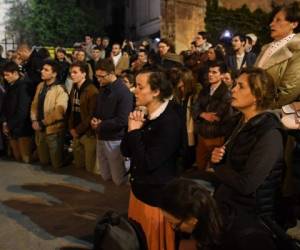 Una multitud de espectadores se arrodillaron en la calle de París para elevar plegarias. Foto: AFP