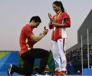 La clavadista se cubrió la boca en asombro con su mano derecha y Qin le entregó una rosa roja en un pequeño contenedor de vidrio.
