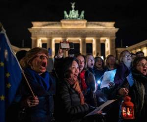 La gente canta el himno de la UE 'Oda a la Alegría' a la medianoche durante un flashmob para marcar el Brexit frente a la Puerta de Brandenburgo de Berlín. Foto. Agencia AFP.
