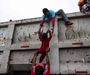 Las imágenes son totalmente desgarradoras. Los migrantes buscan avanzar tras 22 días de camino. Algunas personas les dan jalón, tal y como se observa en la fotografía: Un padre intenta subir a su hijo en un camión. Foto: Agencia AFP