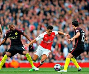 Alexis Sánchez trata de eludir las marcas del Manchester City. Foto: Agencia AFP.