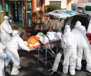 Trabajadores médicos con equipo de protección transfieren a un paciente sospechoso de tener un coronavirus a otro hospital. Foto AFP
