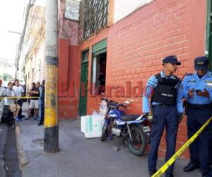 Agentes policiales resguardando la escena del crimen en las afueras de un negocio de venta de camisas deportivas en Tegucigalpa. (Foto: Alex Pérez / EL HERALDO)