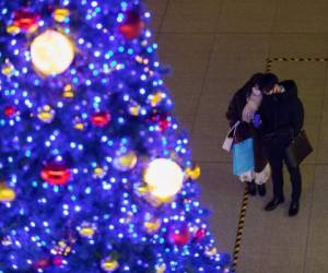 Una pareja con máscaras faciales toma una foto de la exhibición de un árbol de Navidad el día de Navidad en Tokio el viernes 25 de diciembre de 2020 (AP Photo / Hiro Komae)