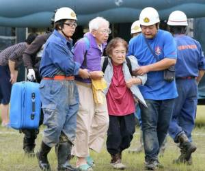 Los miembros de las Fuerzas de Autodefensa de Japón ayudan a una pareja de ancianos después de que fueron evacuados por un helicóptero militar de una zona de desastre después de fuertes lluvias en la prefectura de Kumamoto. Foto: AFP