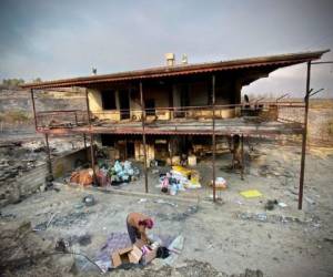 Una mujer guarda cosas frente a una casa en llamas como un incendio forestal masivo que envolvió una región turística del Mediterráneo en la costa sur de Turquía cerca de la ciudad de Manavgat, el 31 de julio de 2021. Foto: AFP