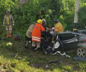 Miembros del Cuerpo de Bomberos rescatando uno de los cuerpos atrapados en el vehículo. Al menos cinco personas murieron en el fatal accidente registrado en El Progreso, Yoro.