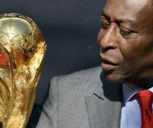 En esta foto tomada el 9 de marzo de 2014, la leyenda del fútbol brasileño Pelé mira el trofeo de la Copa Mundial de la FIFA durante un evento de la FIFA en París. Foto: AFP