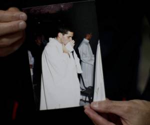 Andrés Gioeni muestra una fotografía de su ceremonia de ordenación para convertirse en sacerdote en 2000, luego de regresar a casa del obispado donde inició el proceso de apostasía en Buenos Aires, Argentina. Foto: AP