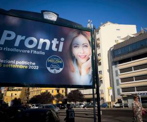 Los peatones pasan frente a un cartel electoral de Giorgia Meloni, líder de extrema derecha del partido Hermanos de Italia.