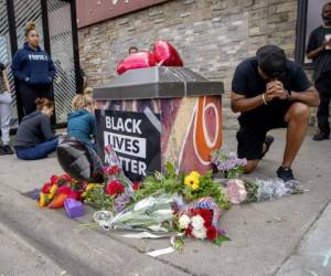 Personas se reúnen alrededor de un memorial improvisado el martes en Minneapolis, cerca del lugar en donde la policía detuvo un día antes a un hombre negro, quien después murió. Foto: AP.