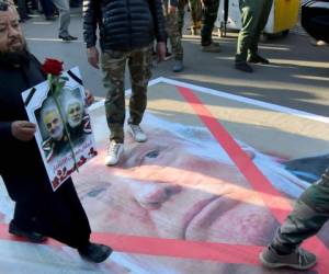 Un hombre iraquí camina sobre un retrato de Donald Trump, presidente de los Estados Unidos. Foto AFP