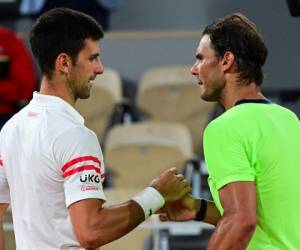El serbio Novak Djokovic (izq.) Y el español Rafael Nadal se dan la mano al final de la semifinal de tenis masculino individual en el día 13 del torneo de tenis Roland Garros 2021 del Abierto de Francia. Foto:AFP