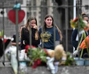 A man man walks past flowers and tributes displayed in memory of the twin mosque massacre victims along the road outside the Linwood mosque (back C) in Christchurch on March 25, 2019. - The slaughter of 50 people at Friday prayers in two Christchurch mosques on March 15 shocked the normally laid-back country and prompted global horror, heightened by the gunman's cold-blooded livestreaming of the massacre. (Photo by ANTHONY WALLACE / AFP)