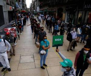 Personas con mascarillas para protegerse del coronavirus aguardan a cruzar una calle en el centro de la Ciudad de México. En las últimas medidas el gobierno redujo las restricciones. Foto: Agencia AP