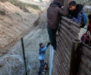 Migrantes intentando cruzar en la frontera de Tijuana con San Diego, California. (AFP)