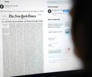 Esta imagen muestra a una mujer mirando la pantalla de una computadora con un tweet de la cuenta del periódico New York Times que muestra la primera página de la primera edición del 24 de mayo de 2020, con una lista de 1,000 nombres impresos, que representan el 1% de las vidas perdidas debido a la nueva pandemia de coronavirus, COVID-1.