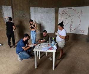 A un voluntario le extraen sangre del brazo para que el artista colombiano Julián Castillo la use para pintar un mural que representa al cantante puertorriqueño René Pérez.