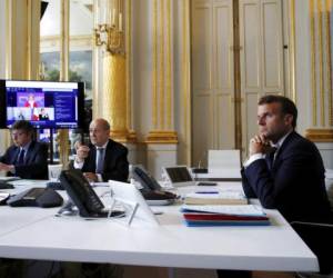 El presidente francés Emmanuel Macron (d) y el ministro de relaciones exteriores francés Jean-Yves le Drian (cent) en una videoconferencia sobre el coronavirus en el Palacio de los Elíseos en París. Foto: AP.